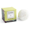A white, handmade Energizing Joy Bath Bomb next to its citrus-themed yellow packaging, a perfect addition to natural bath bomb sets.