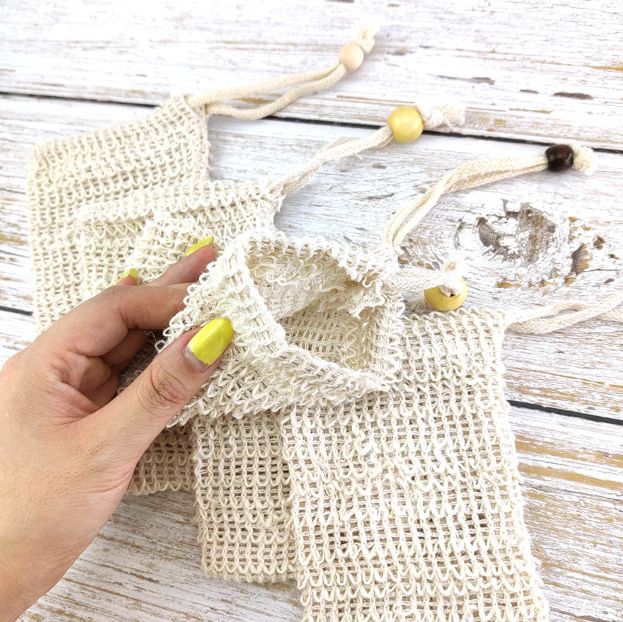 Hand holding a beige mesh bag on a wooden surface