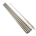 A set of four stainless steel straw pieces laid out diagonally on a white background next to a thin metal cleaning brush.